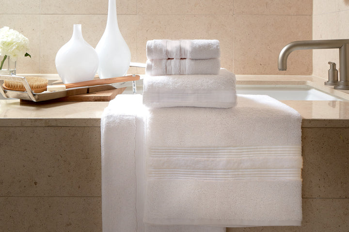 Thomaston Mills American Luxury Magnolia hospitality towels folded and sitting on the side of a tub.